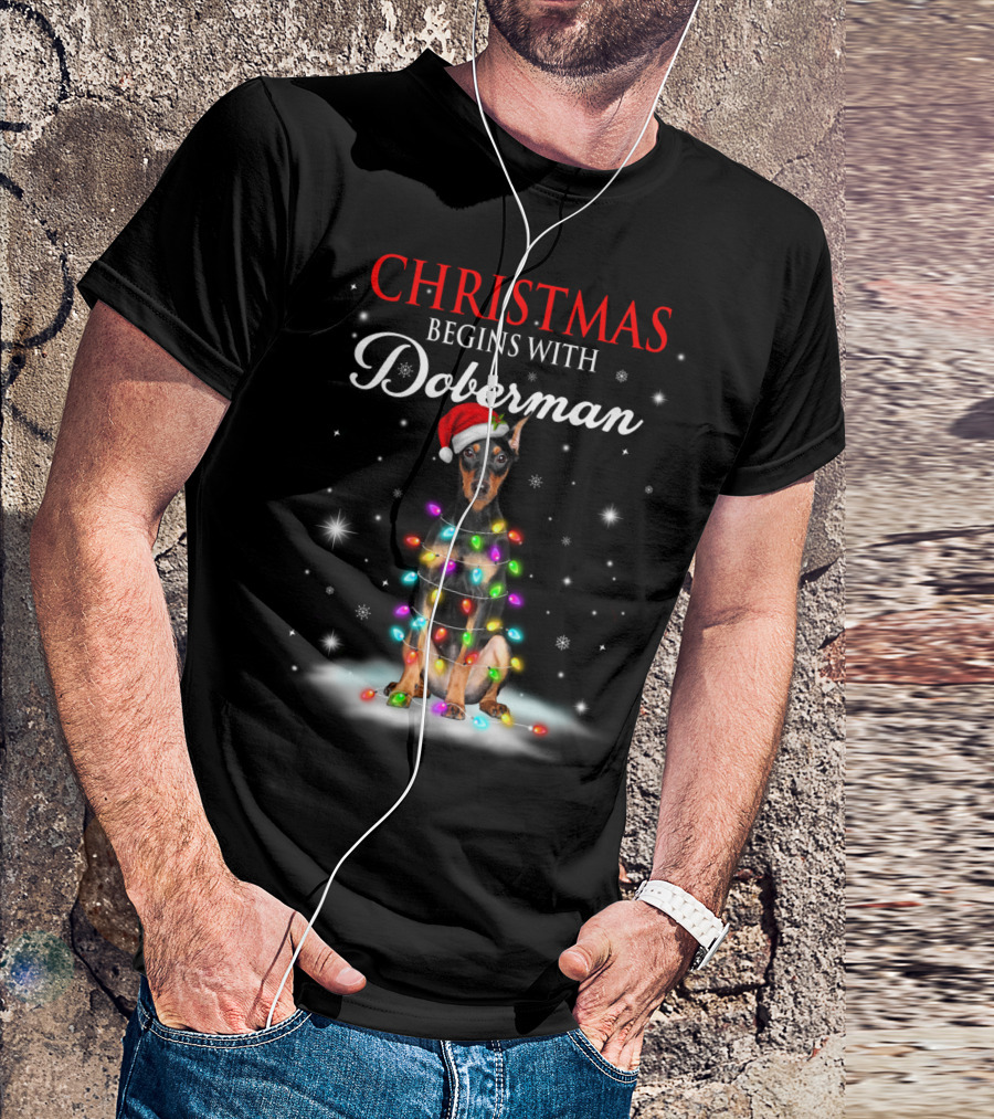 Christmas Begins With Doberman Wrapped In Holiday Lights And Santa Hat Snowflakes T-Shirt