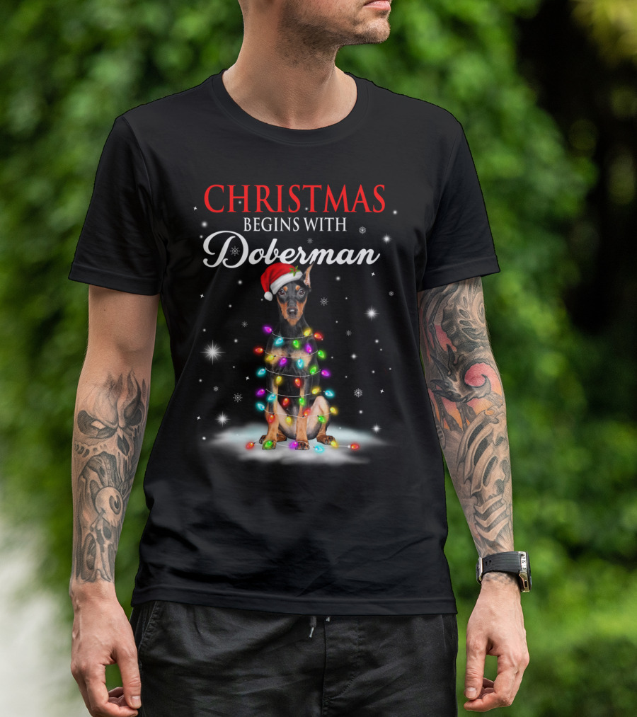 Christmas Begins With Doberman Wrapped In Holiday Lights And Santa Hat Snowflakes T-Shirt